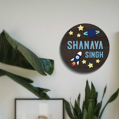 Round space name plate on a bedroom door with stars, a rocket and a ringed planet