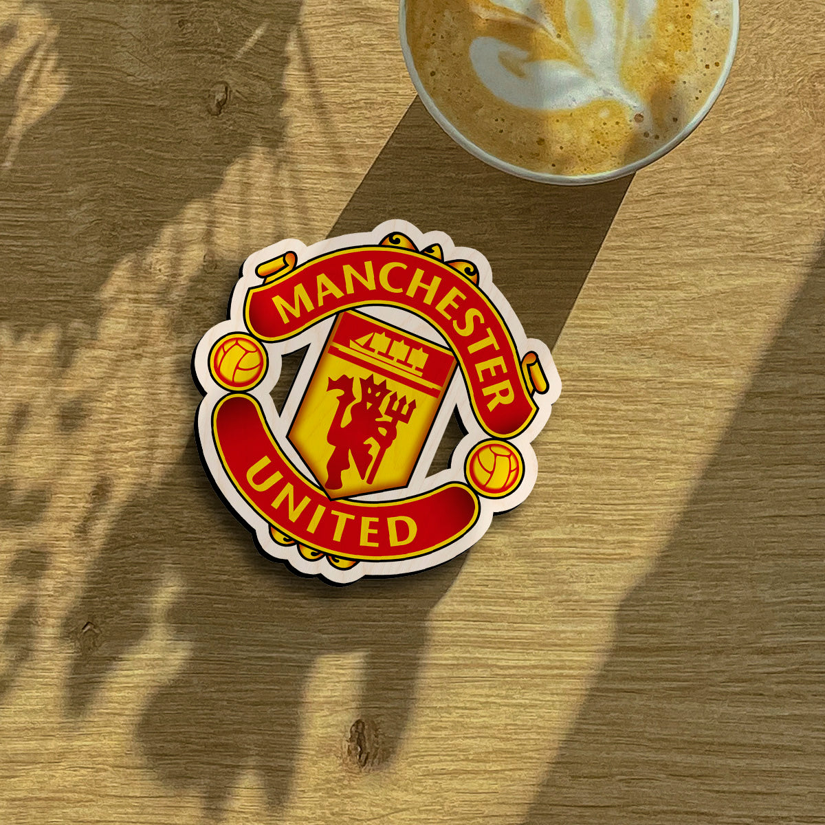 Manchester united fridge magnet on a clean backdrop showing red devil + trident inside yellow shield with scroll banners.