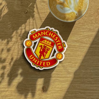 Manchester united fridge magnet on a clean backdrop showing red devil + trident inside yellow shield with scroll banners.