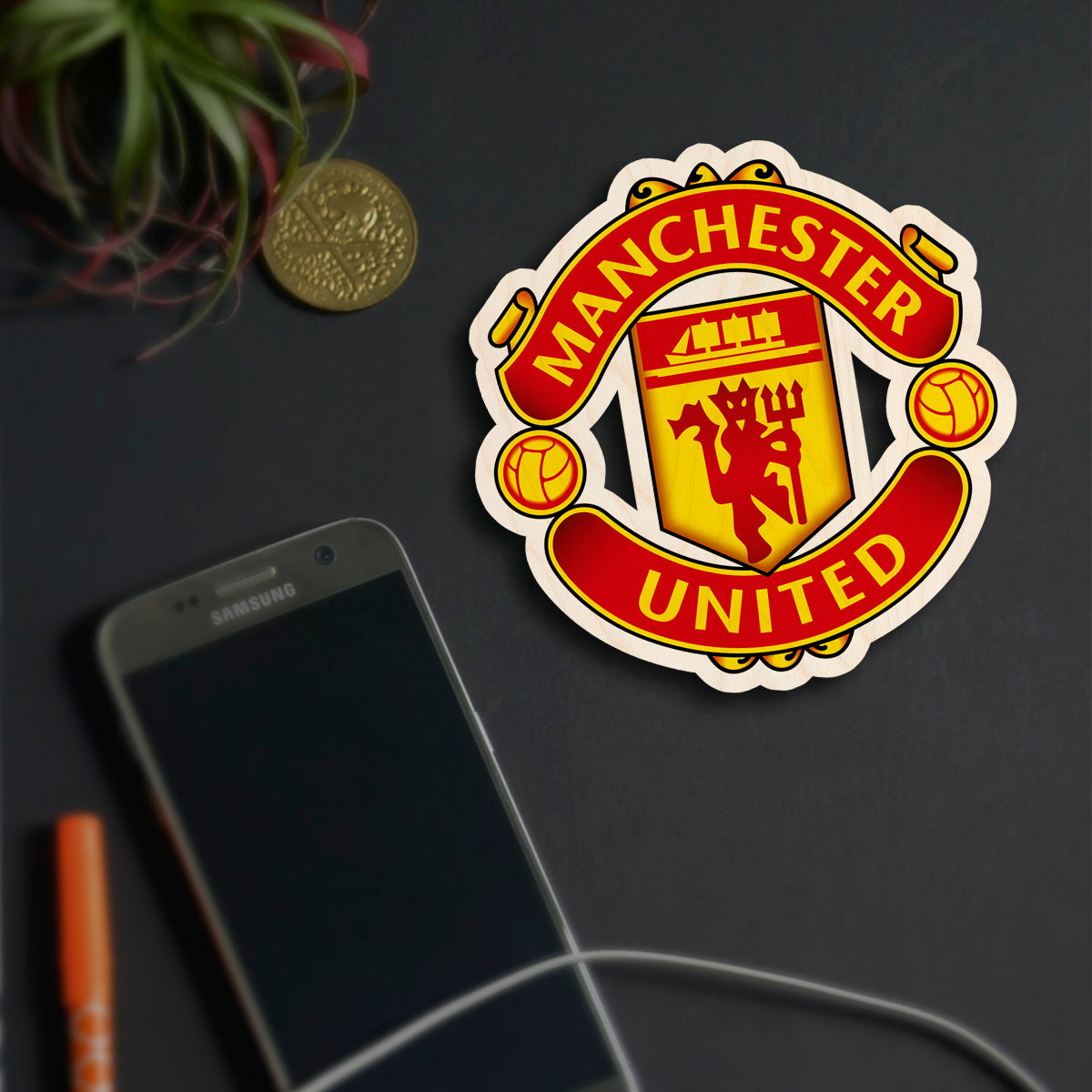 Detail shot of the manchester united fridge magnet in birch wood with magnet back and clean backdrop styling.