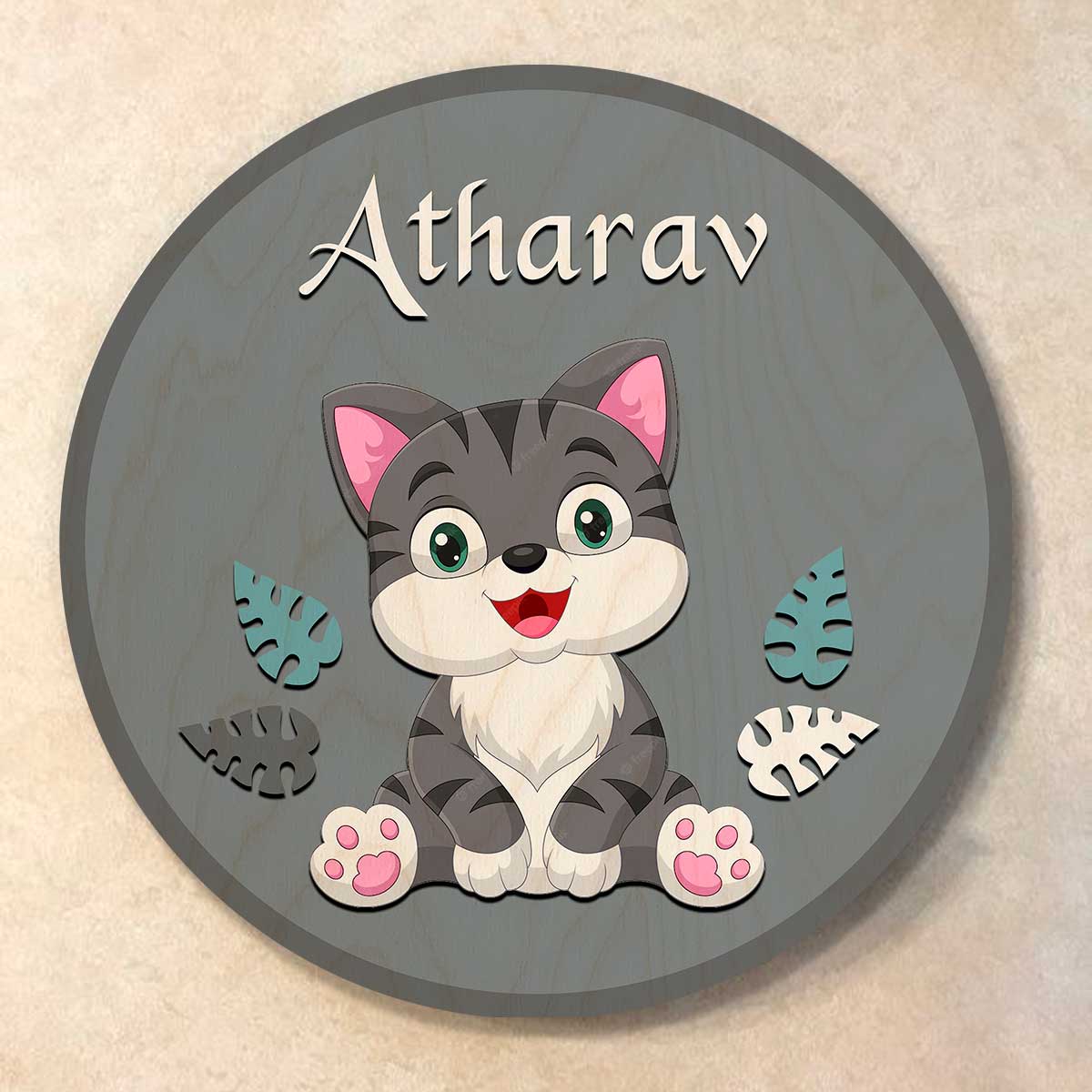 Cute grey tabby cat with wooden leaf cutouts on round grey cat name plate for kids