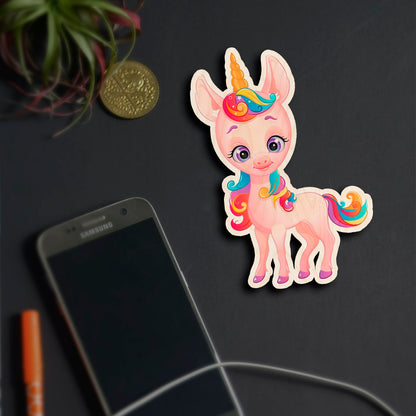 Alternate angle on the kids fridge magnet, showing cartoon unicorn silhouette with rainbow mane and tail, in birch wood.