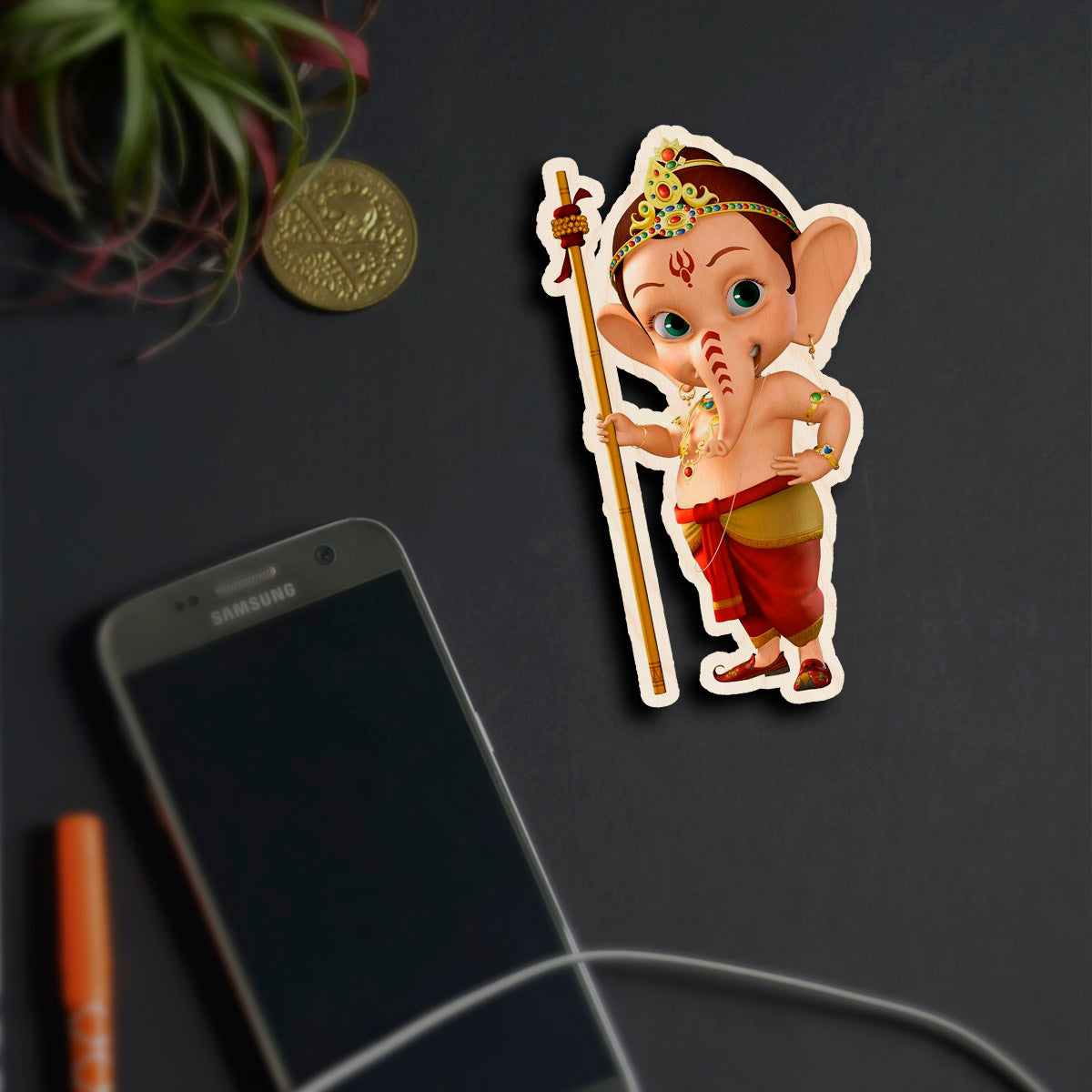 Alternate angle on the god fridge magnet, showing cartoon baby Ganesha with staff and tiara silhouette, in birch wood.