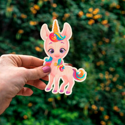 Detail crop of the kids fridge magnet, with cartoon unicorn silhouette with rainbow mane and tail, on birch wood face.