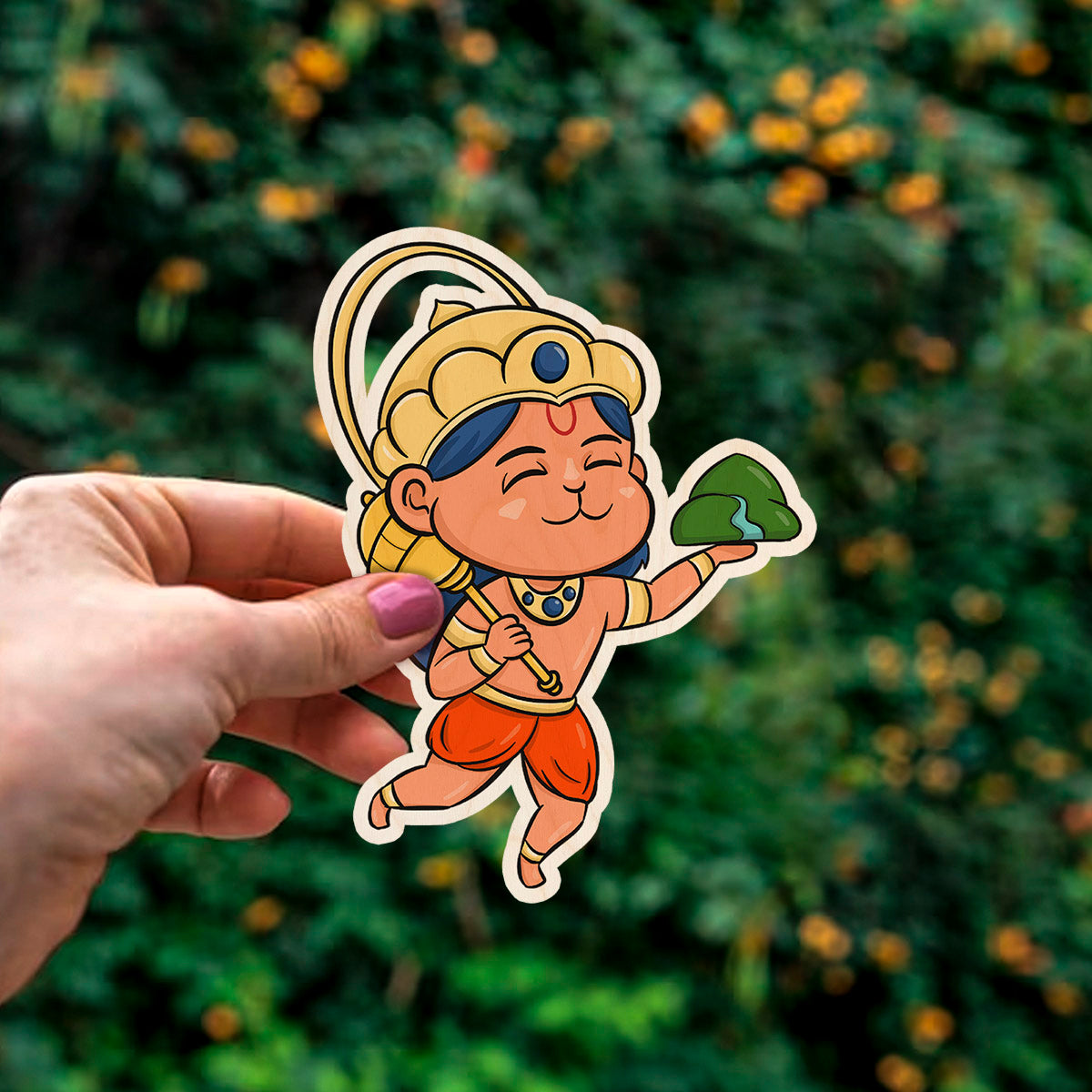 Detail crop of the god fridge magnet, with cartoon Hanuman with Sanjivani mountain and golden crown, on birch wood face.