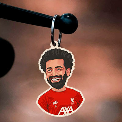 Detail of the wooden keychain, with salah caricature with signature curls in the 2021-22, in birch wood.