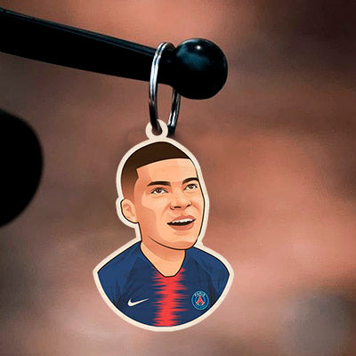 Detail of the football keychain, with mbappe cartoon in PSG navy + red center-stripe kit with, in birch wood.