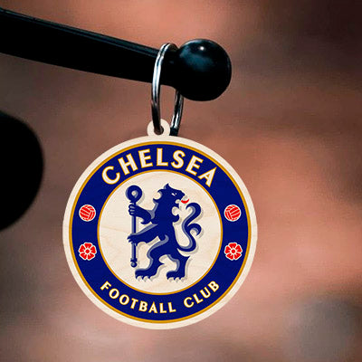 Detail of the football keychain, with chelsea blue rampant lion roundel with gold ring text, in birch wood.
