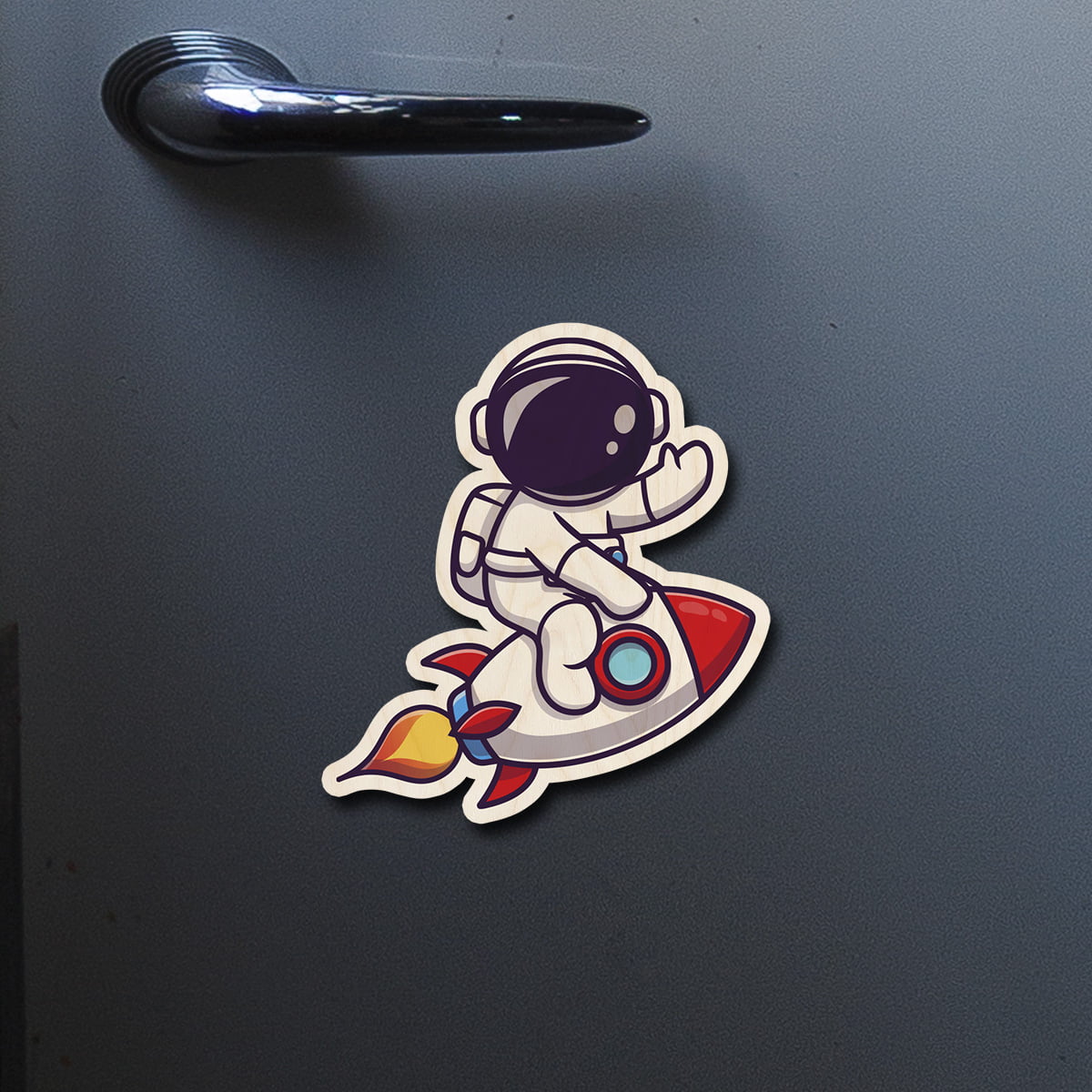On-fridge lifestyle shot of the kids fridge magnet, showing cartoon astronaut on red rocket with flame trail.