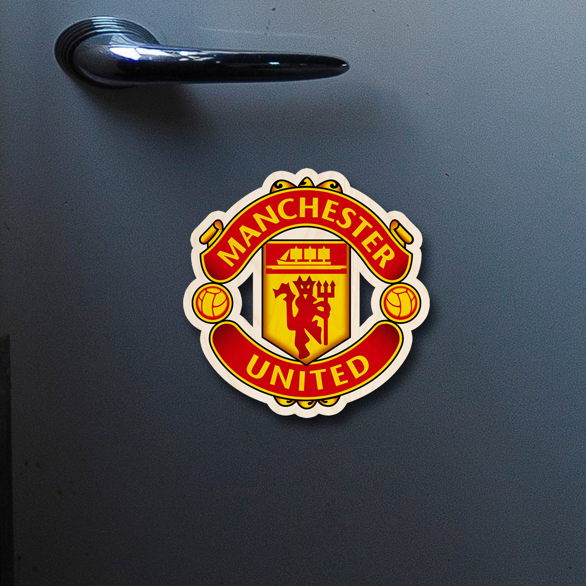 On-fridge lifestyle shot of the manchester united fridge magnet, clipped to a stainless surface.