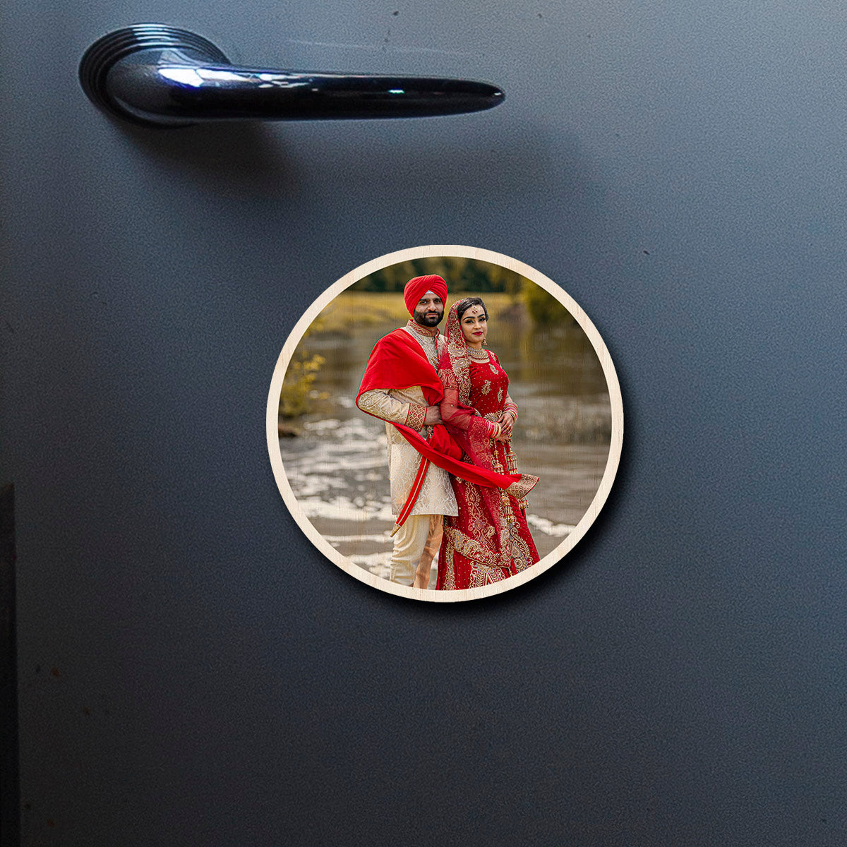 On-fridge lifestyle shot of the couple fridge magnet, showing circle contour-cut silhouette with full-bleed couple photo.
