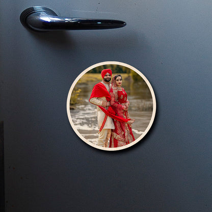 On-fridge lifestyle shot of the couple fridge magnet, showing circle contour-cut silhouette with full-bleed couple photo.
