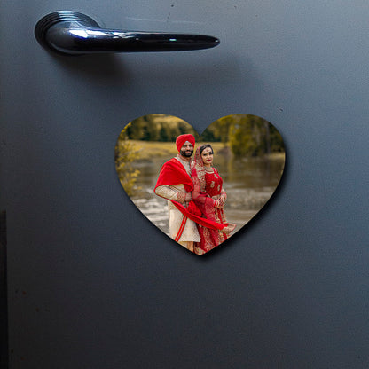 On-fridge lifestyle shot of the couple fridge magnet, showing heart contour-cut silhouette with full-bleed couple photo.