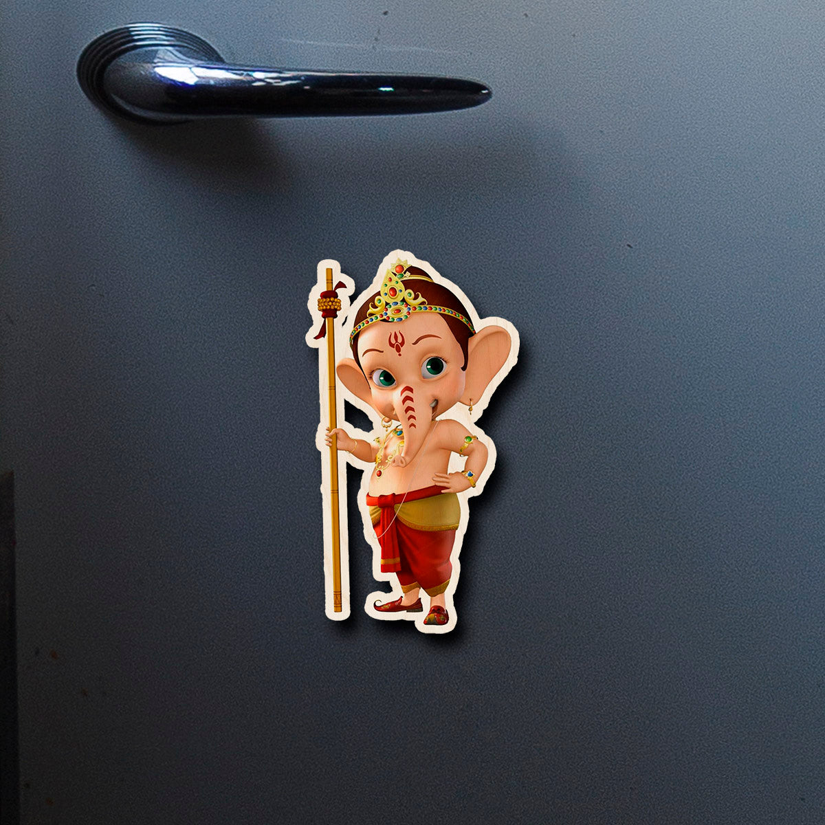 On-fridge lifestyle shot of the god fridge magnet, showing cartoon baby Ganesha with staff and tiara silhouette.