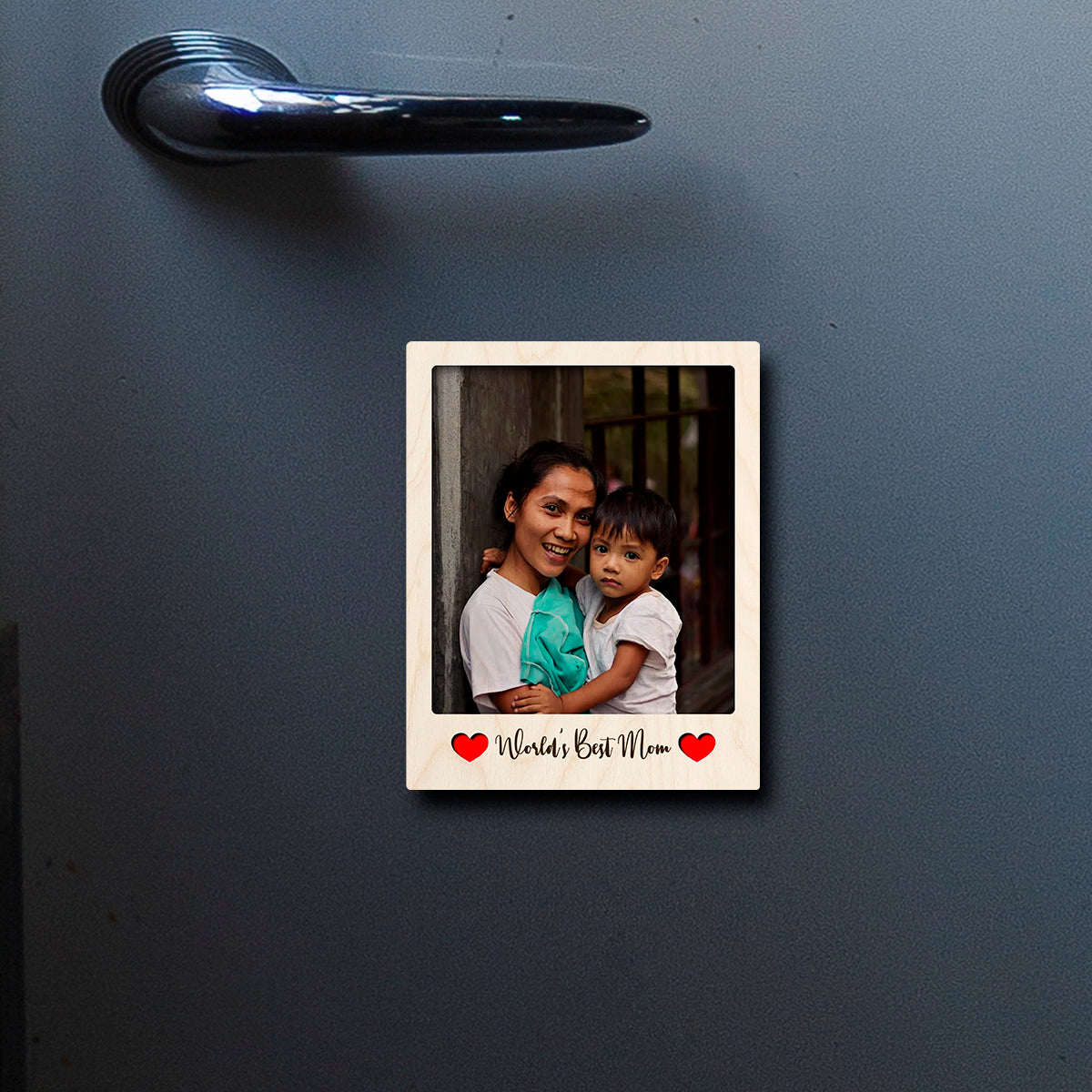 On-fridge lifestyle shot of the mom fridge magnet, showing polaroid frame with Mom-tribute cursive.