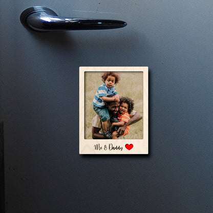 On-fridge lifestyle shot of the dad fridge magnet, showing polaroid with 'Dad' label, clipped to a stainless surface.