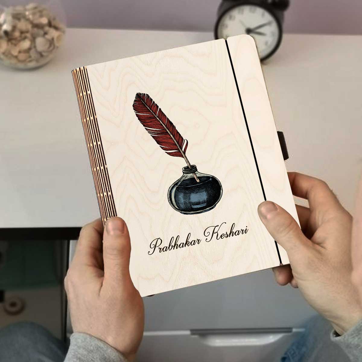 Detail crop on the personalized diary cover, with color-printed quill + navy inkwell illustration with, sharp birch grain.