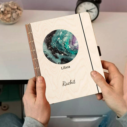 Personalized diary cover on a clean backdrop showing teal-green nebula with Libra diamond-cluster constellation.