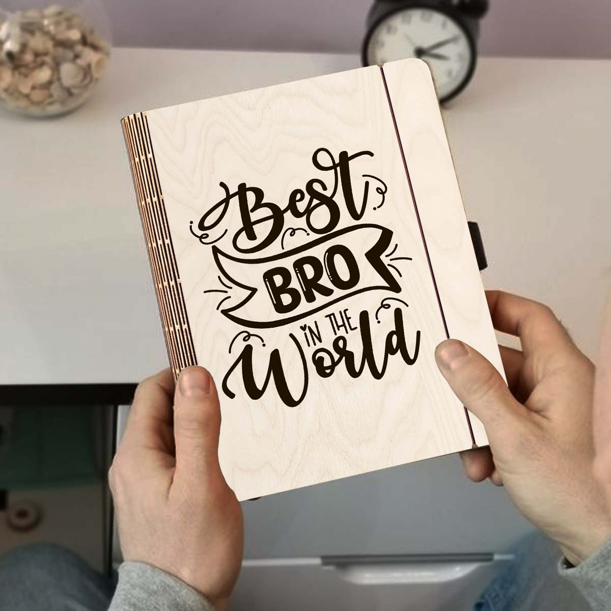 Detail crop on the wooden notebook cover, with hand-lettered brother-tribute script with ribbon banner, sharp birch grain.
