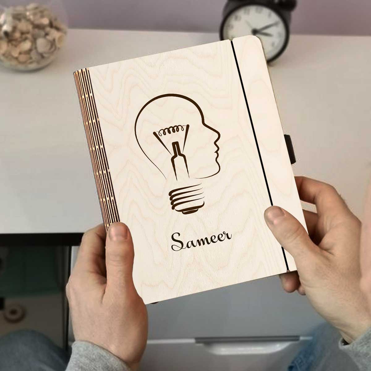 Detail crop on the personalized diary cover, with lightbulb-head silhouette (head profile fused with a bulb).