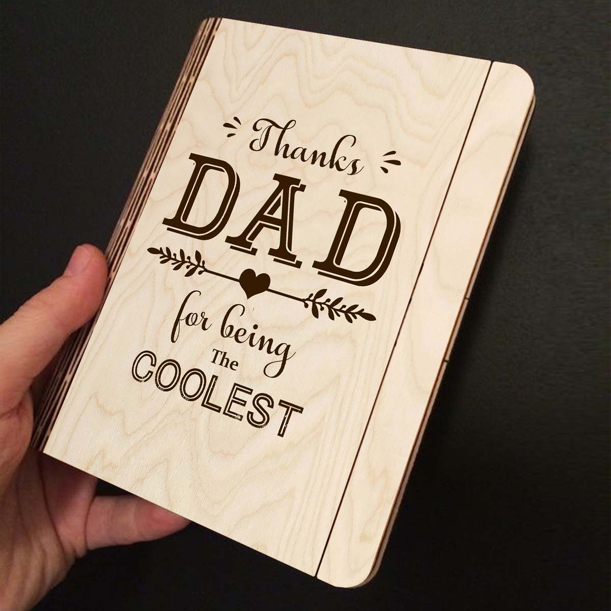 Open spread of the wooden notebook, with thanks DAD' typography with heart-arrow vines, and ruled inner pages.