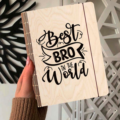 Alternate angle on the wooden notebook, showing hand-lettered brother-tribute script with ribbon banner, in birch wood.