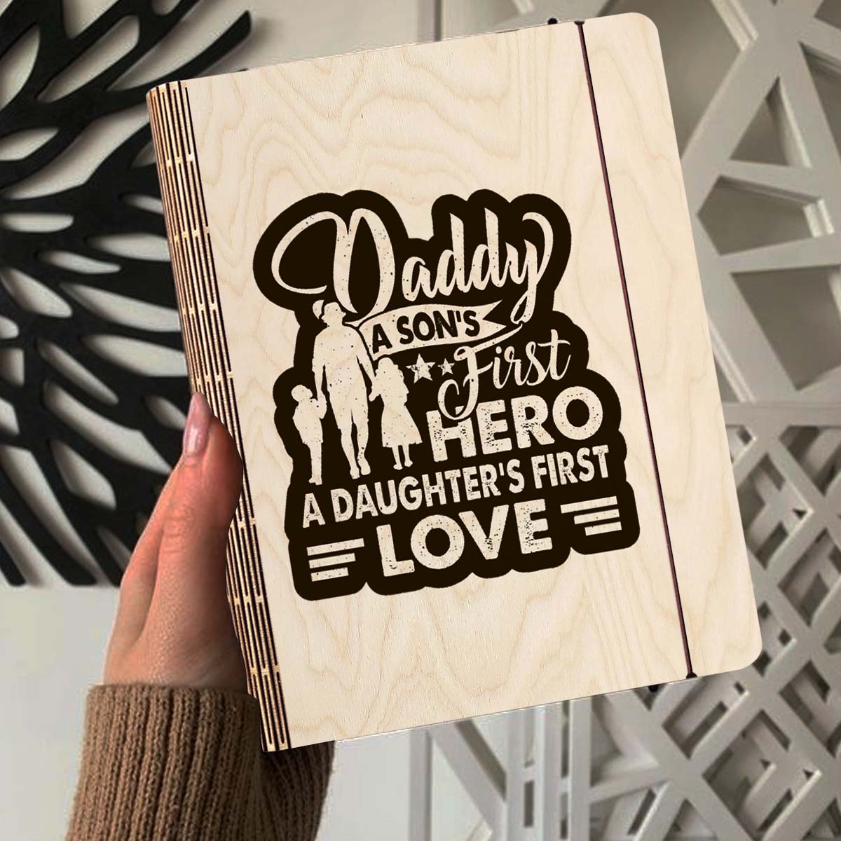 Alternate angle on the wooden notebook, showing father-and-children silhouette plus 'Daddy first hero /, in birch wood.