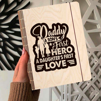 Alternate angle on the wooden notebook, showing father-and-children silhouette plus 'Daddy first hero /, in birch wood.