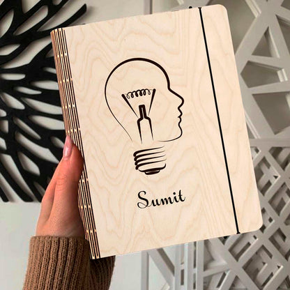 Alternate angle on the personalized diary, showing lightbulb-head silhouette (head profile fused with a bulb).