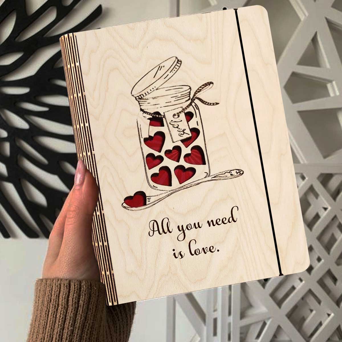 Alternate angle on the wooden notebook, showing mason jar with red hearts + 'All You Need Is Love' cursive, in birch wood.