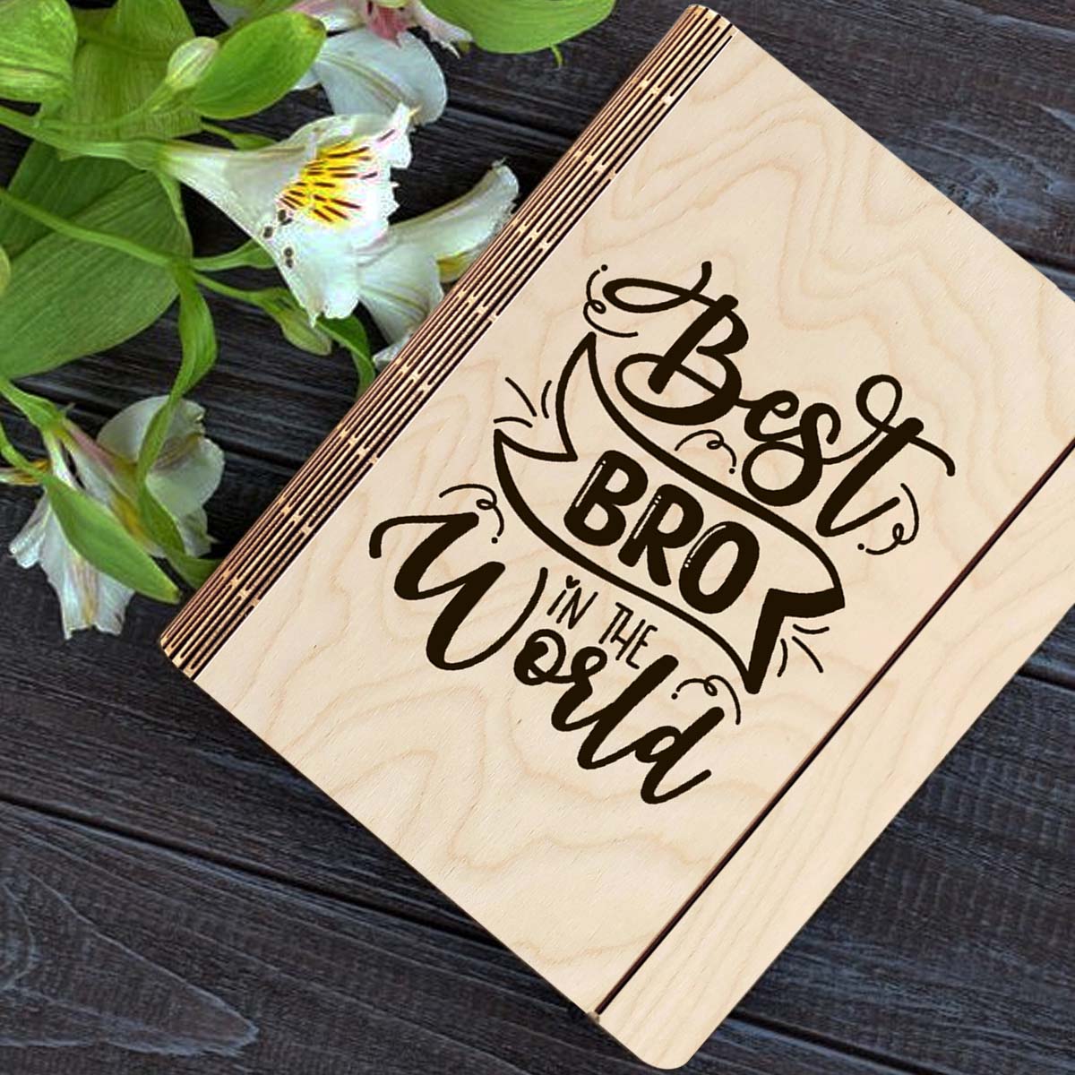 Wooden notebook cover on a clean backdrop showing hand-lettered brother-tribute script with ribbon banner.