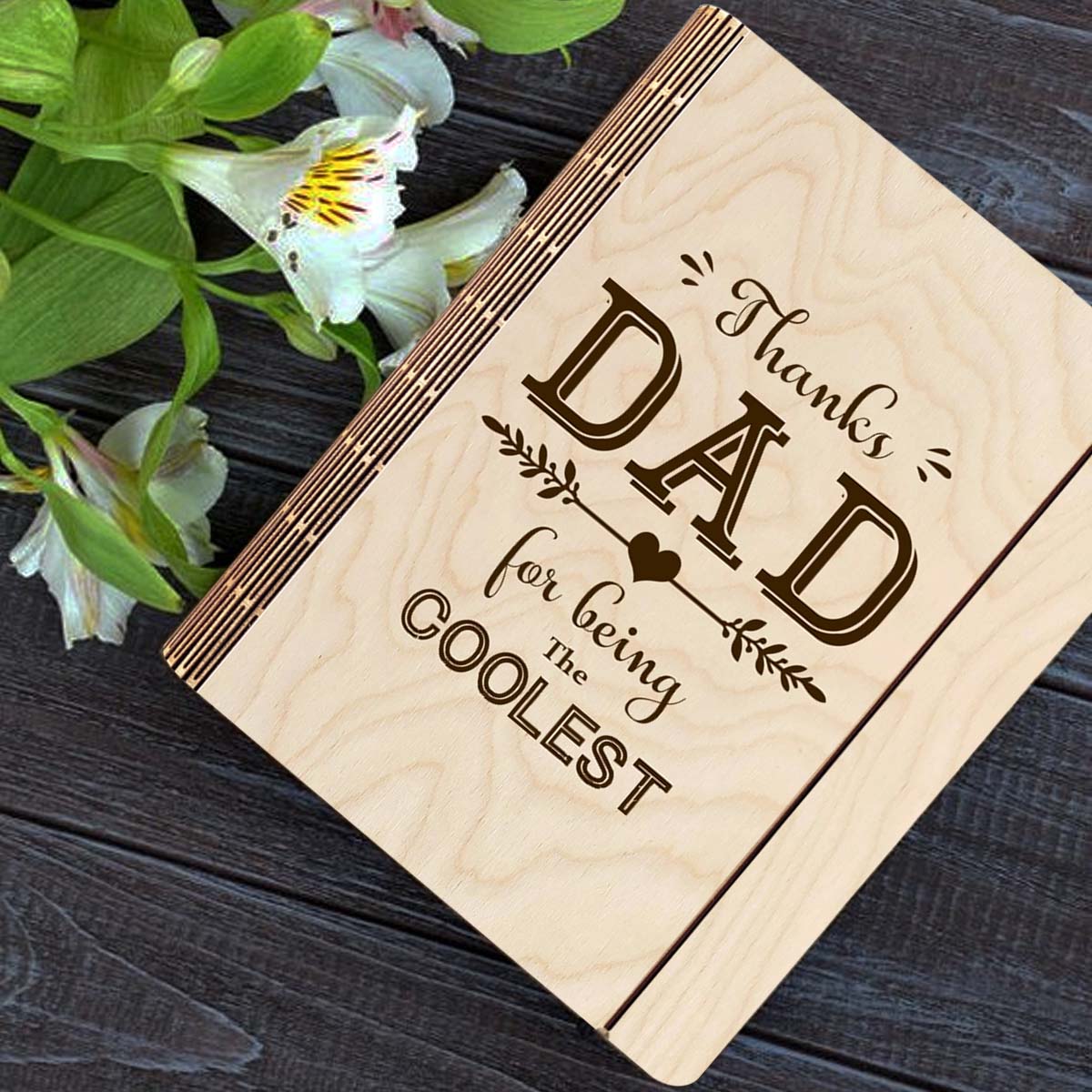 Wooden notebook cover on a clean backdrop showing thanks DAD' typography with heart-arrow vines, on a 21x17 cm birch wood.