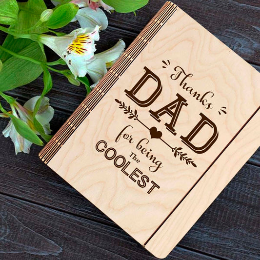 Wooden notebook cover on a clean backdrop showing thanks DAD' typography with heart-arrow vines, on a 21x17 cm birch wood.
