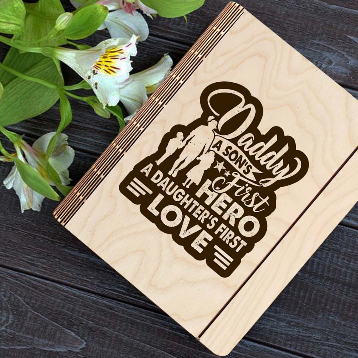 Wooden notebook cover on a clean backdrop showing father-and-children silhouette plus 'Daddy first hero /.