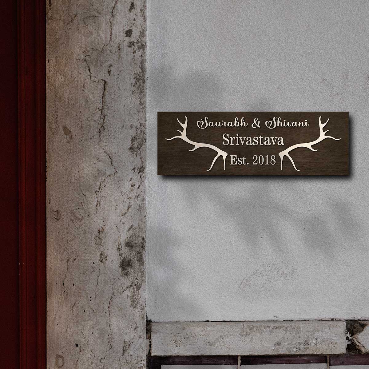 Personalised antler family name plate styled on an entrance wall in dark wood