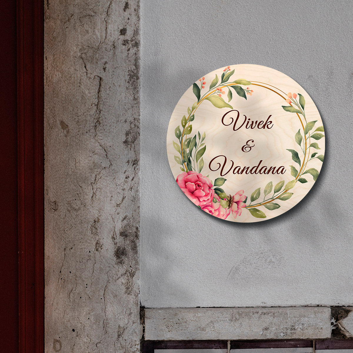 Scattered bloom couple name board with both names inside a golden floral ring on light wood