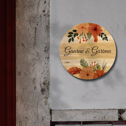 Boho wooden name board with folk-art flowers in terracotta and sage framing two names on round birch