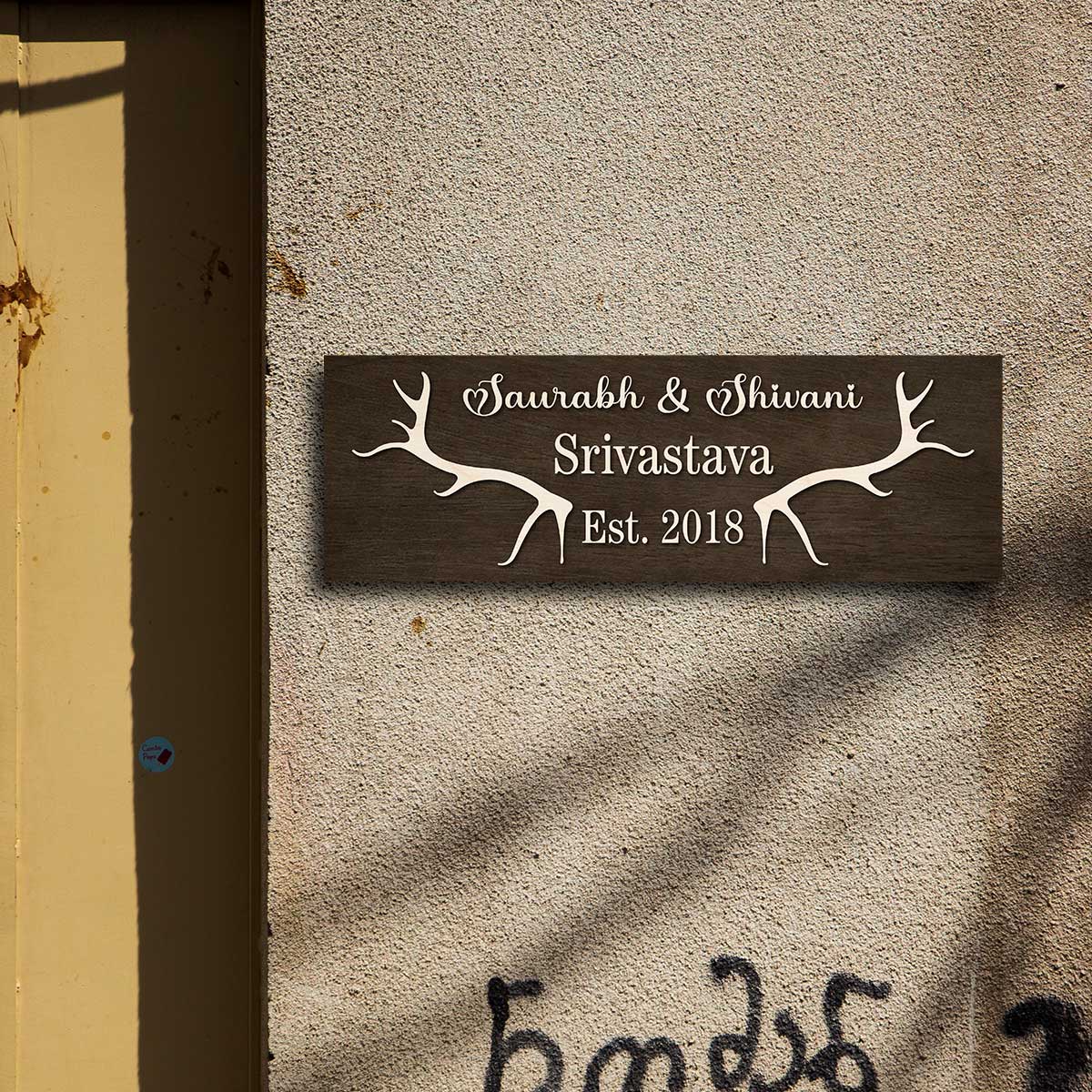 Close-up of cream antler motif and raised lettering on the dark wooden nameplate