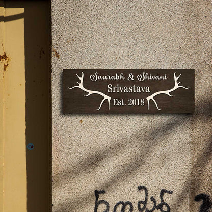Close-up of cream antler motif and raised lettering on the dark wooden nameplate
