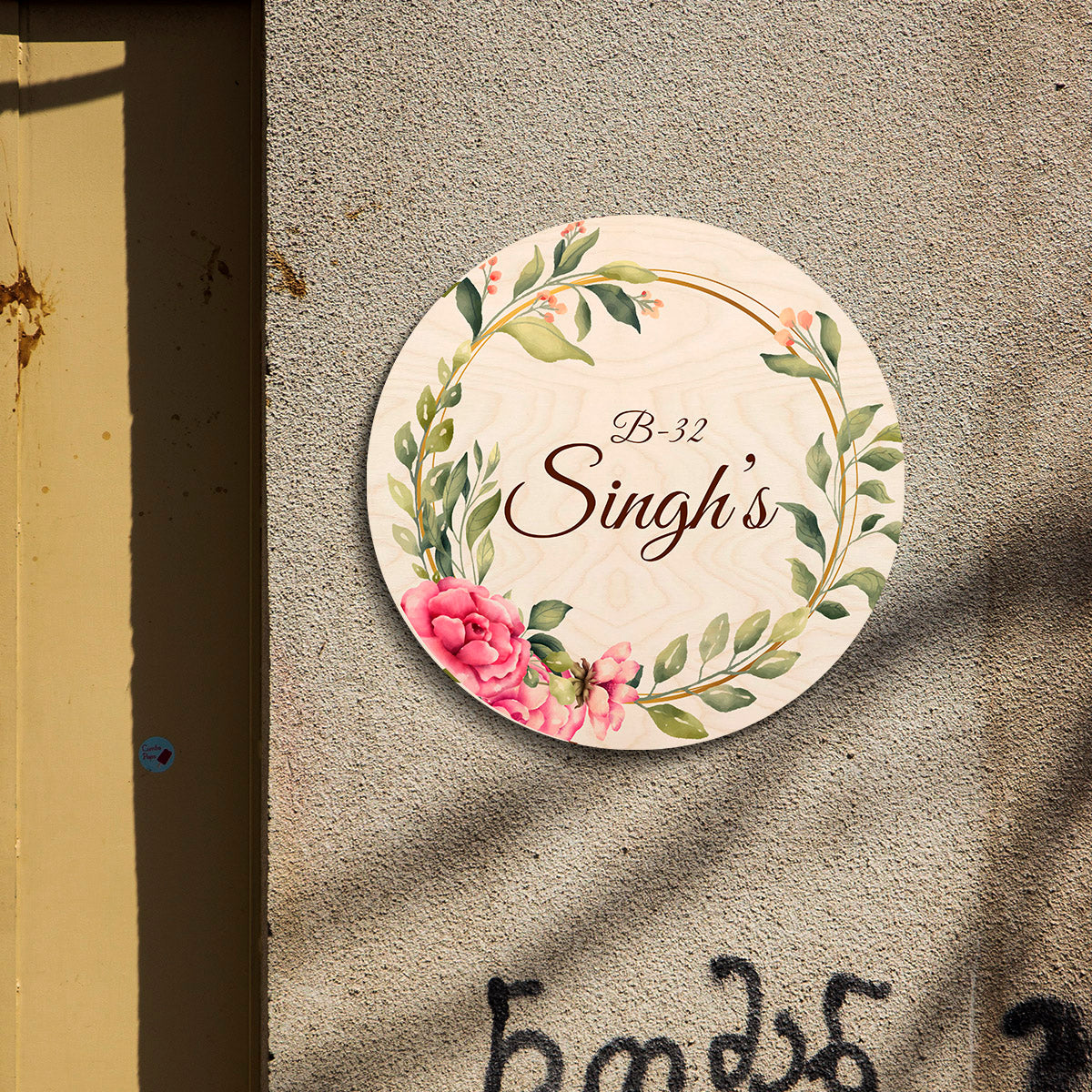 Round couple name plate displayed by a front door, two names in warm brown script