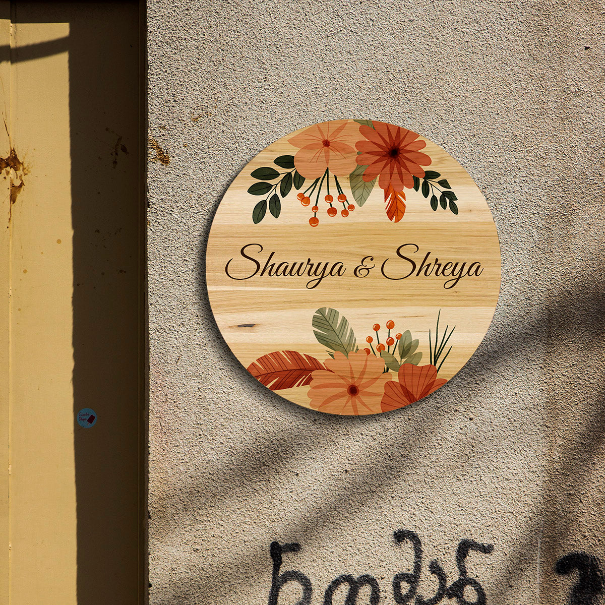 Round bohemian name plate mounted by a house entrance, names in dark brown script over wood grain