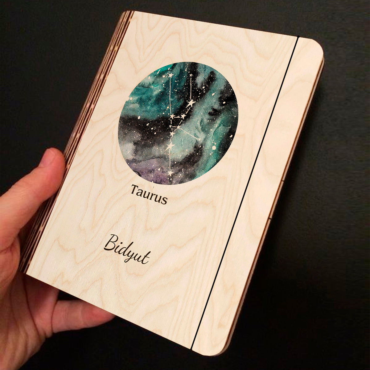Alternate angle on the personalized diary, showing teal-blue nebula with Taurus V-shape Hyades cluster and, in birch wood.