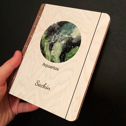 Alternate angle on the personalized diary, showing green-blue-black nebula with Aquarius zigzag-wave, in birch wood.