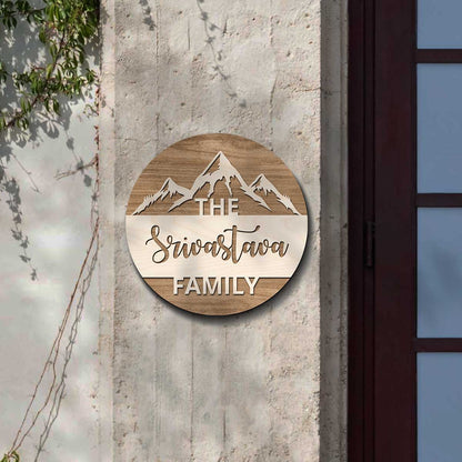 Mountain top design family name plate with snow-capped peaks and surname on brown wood