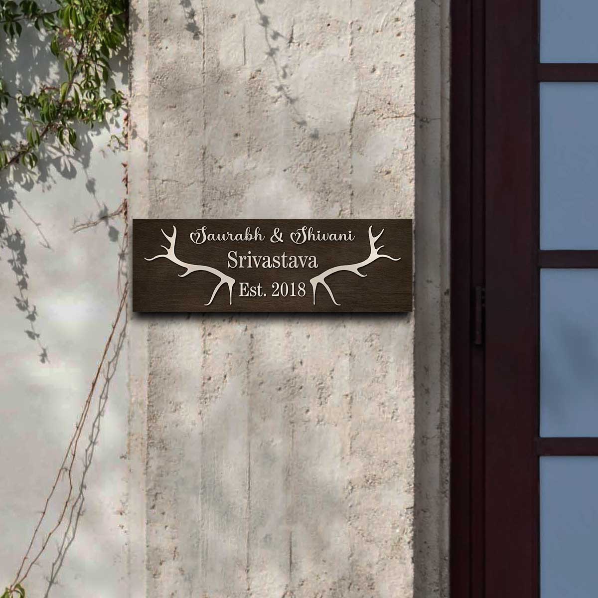 Slim antler name sign on a front door with raised cursive names and Est. year