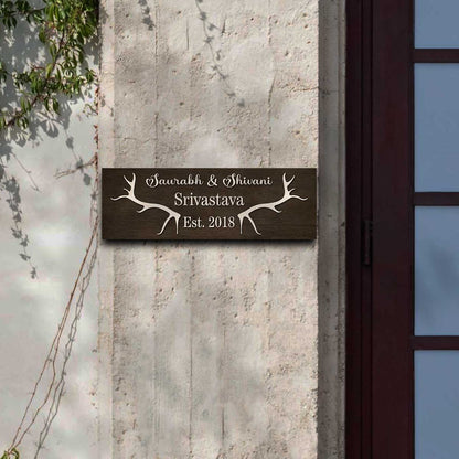 Slim antler name sign on a front door with raised cursive names and Est. year