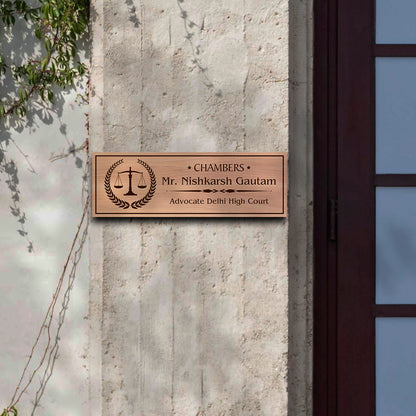 Slim advocate name plate on a chamber door in walnut-brown print on golden wood